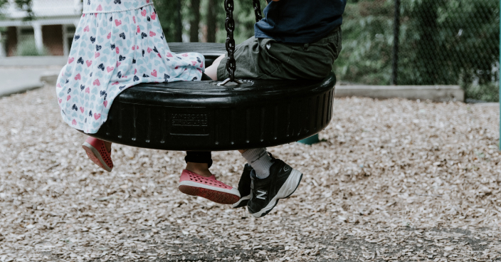 Children playing on a tire swing.